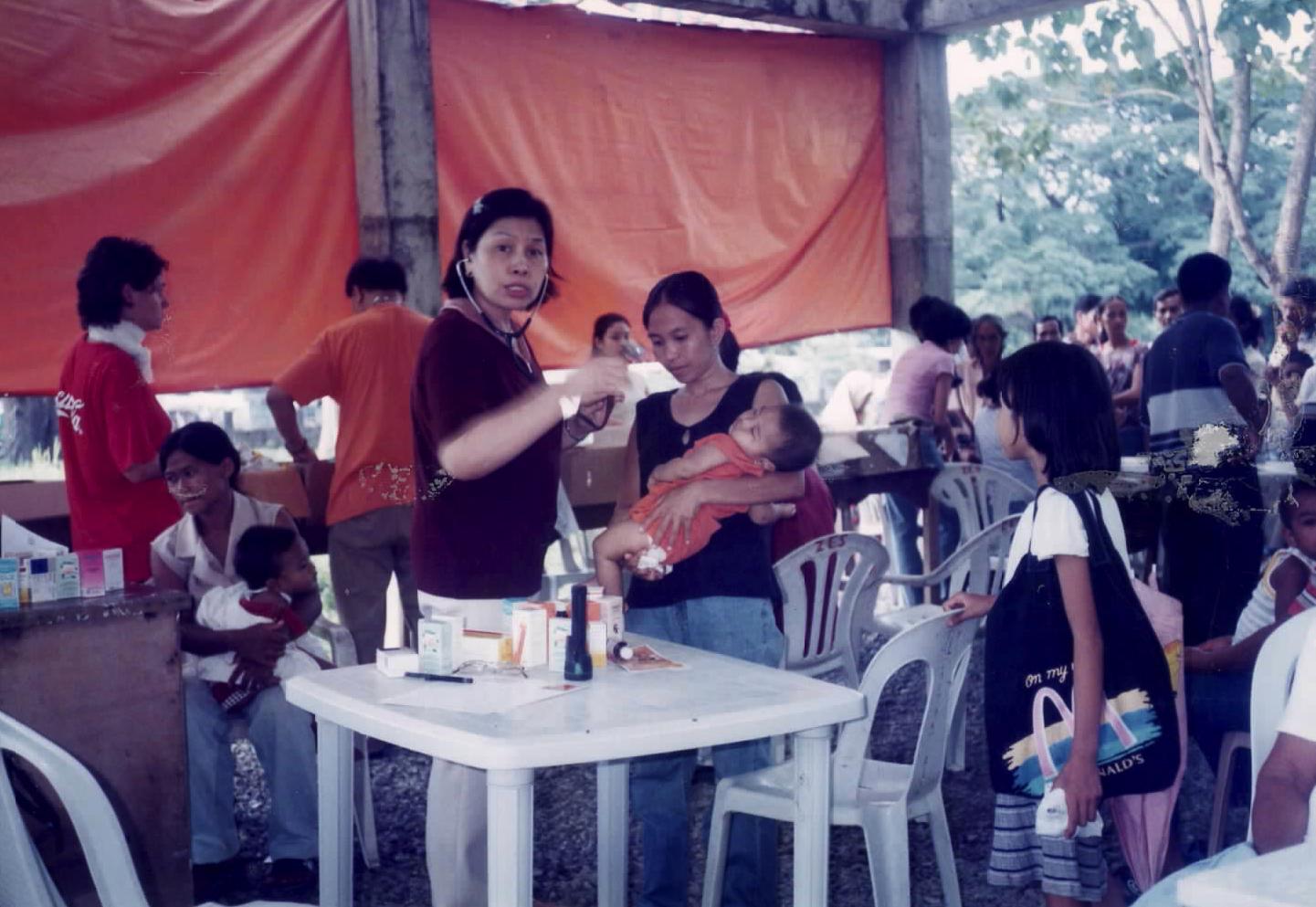 Sacred Heart healthcare professional attending to a mother and child during a community medical mission